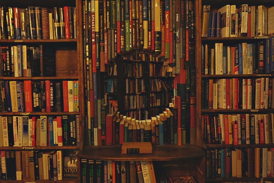 A close-up view of various books in a slightly tilted bookshelf.