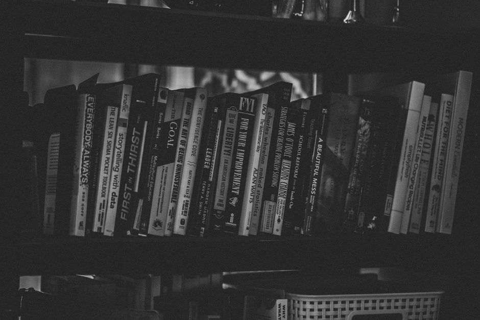 A black and white close-up of a bookshelf filled with diverse books, showcasing a variety of literature.