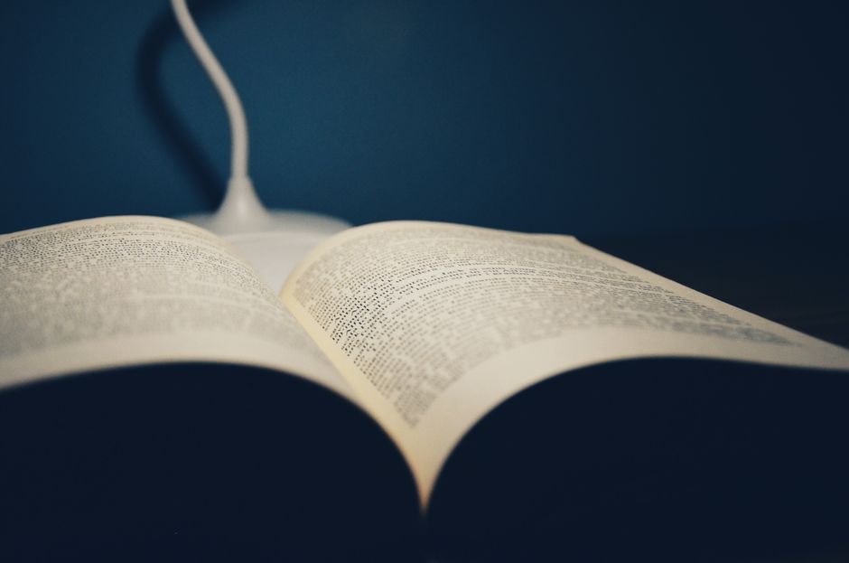 A close-up of a stack of open books with pages fanned out, capturing a study atmosphere.