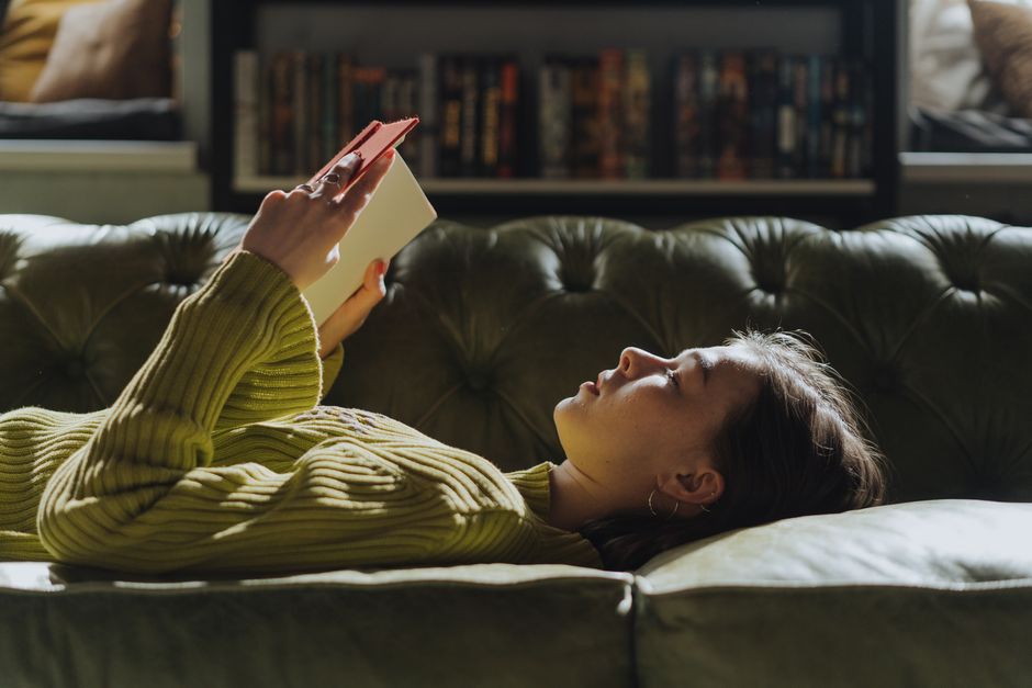 Asian woman reading a book outdoors, capturing a serene moment of relaxation in nature.