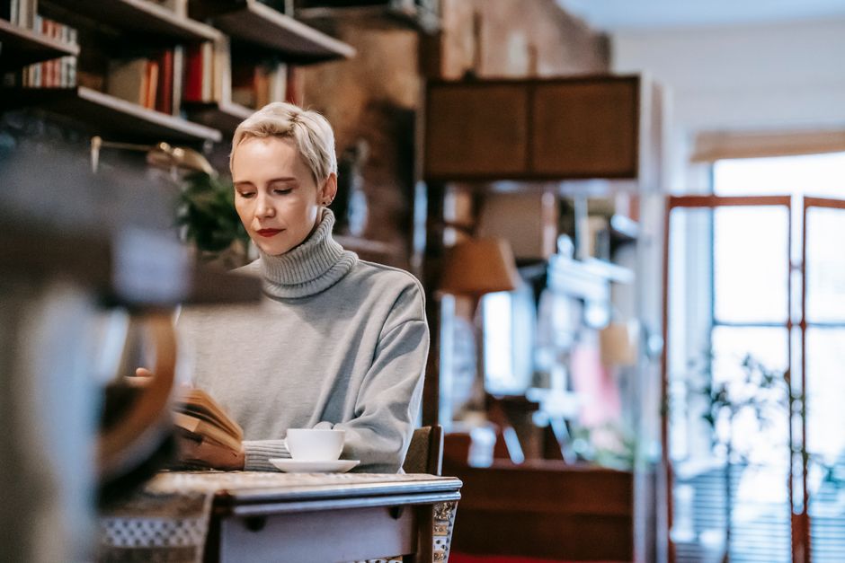 Woman enjoying relaxation by reading a book on a cozy couch indoors.